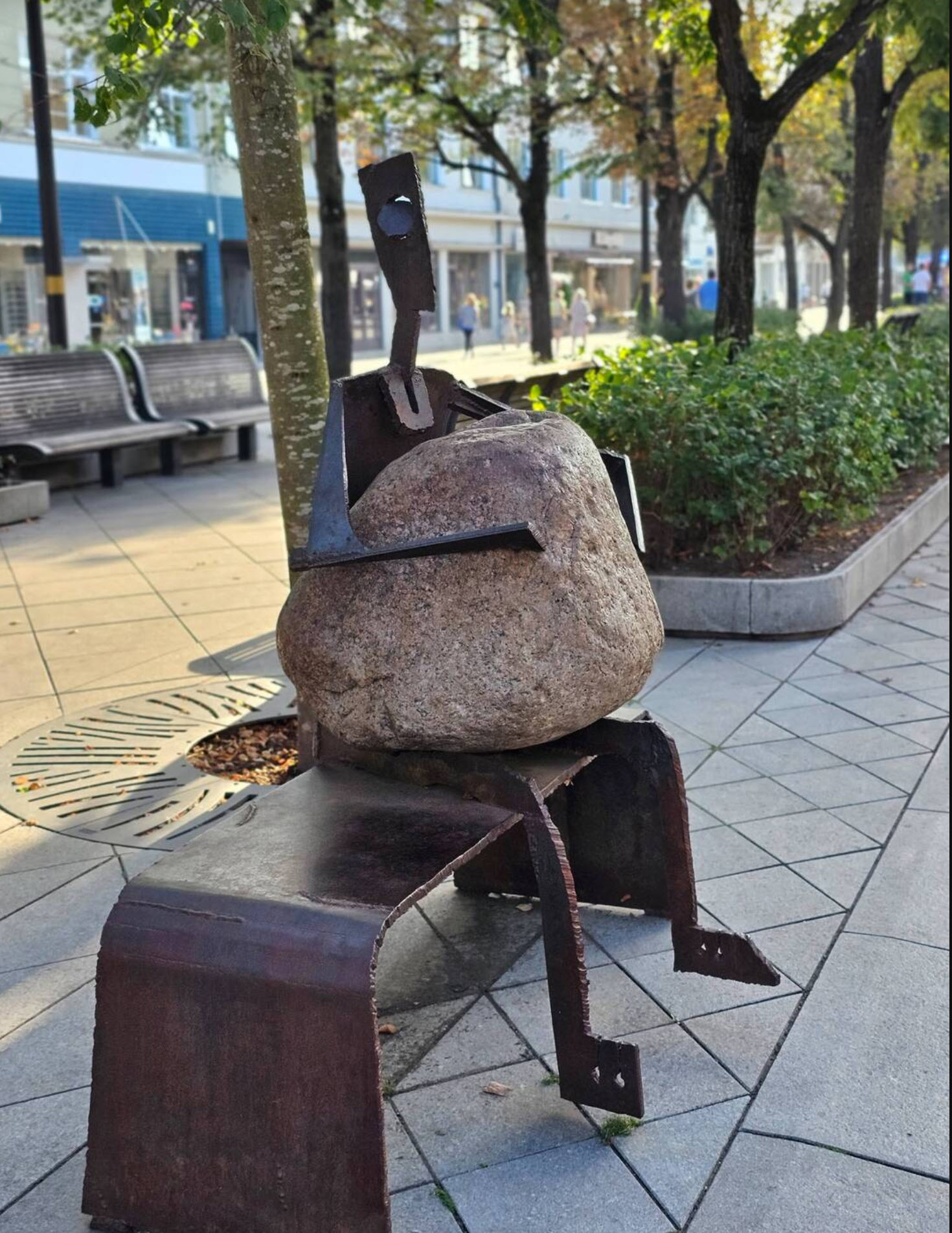 Skulptur einer Figur, die eine schwere Steinlast auf dem Schoß trägt