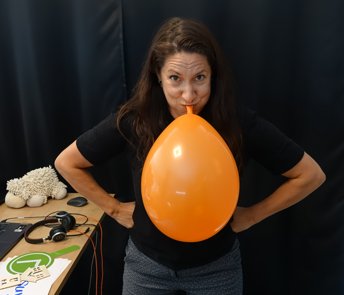 Susi Nocker bläst einen orangefarbenen Luftballon auf
