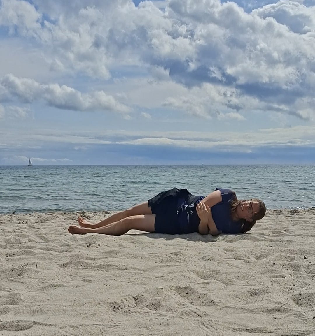 Susi Nocker liegt entspannt am Strand, hinter ihr das Meer